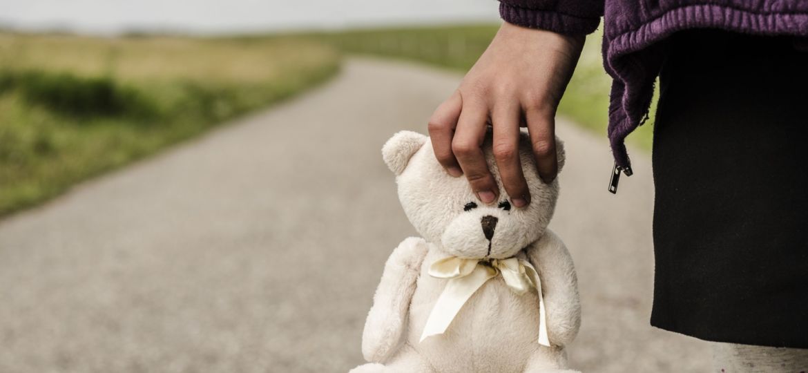 Refugee child goes on the road with her teddy bear