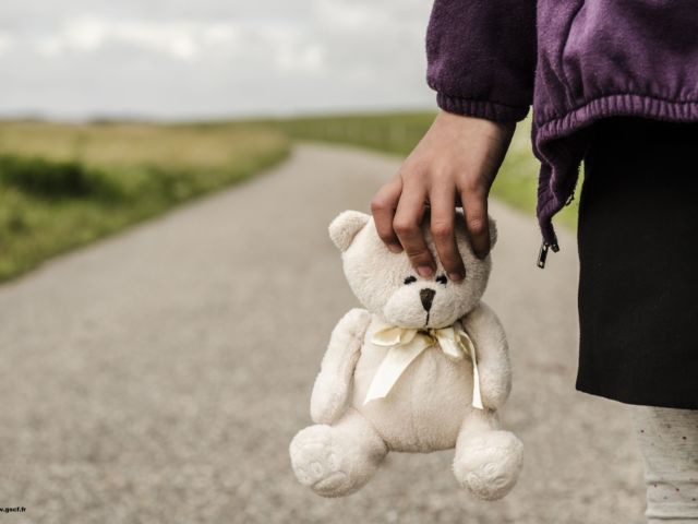 Refugee child goes on the road with her teddy bear
